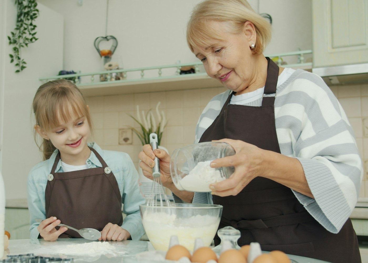 A grandmother and granddaughter baking together in a home kitchen
