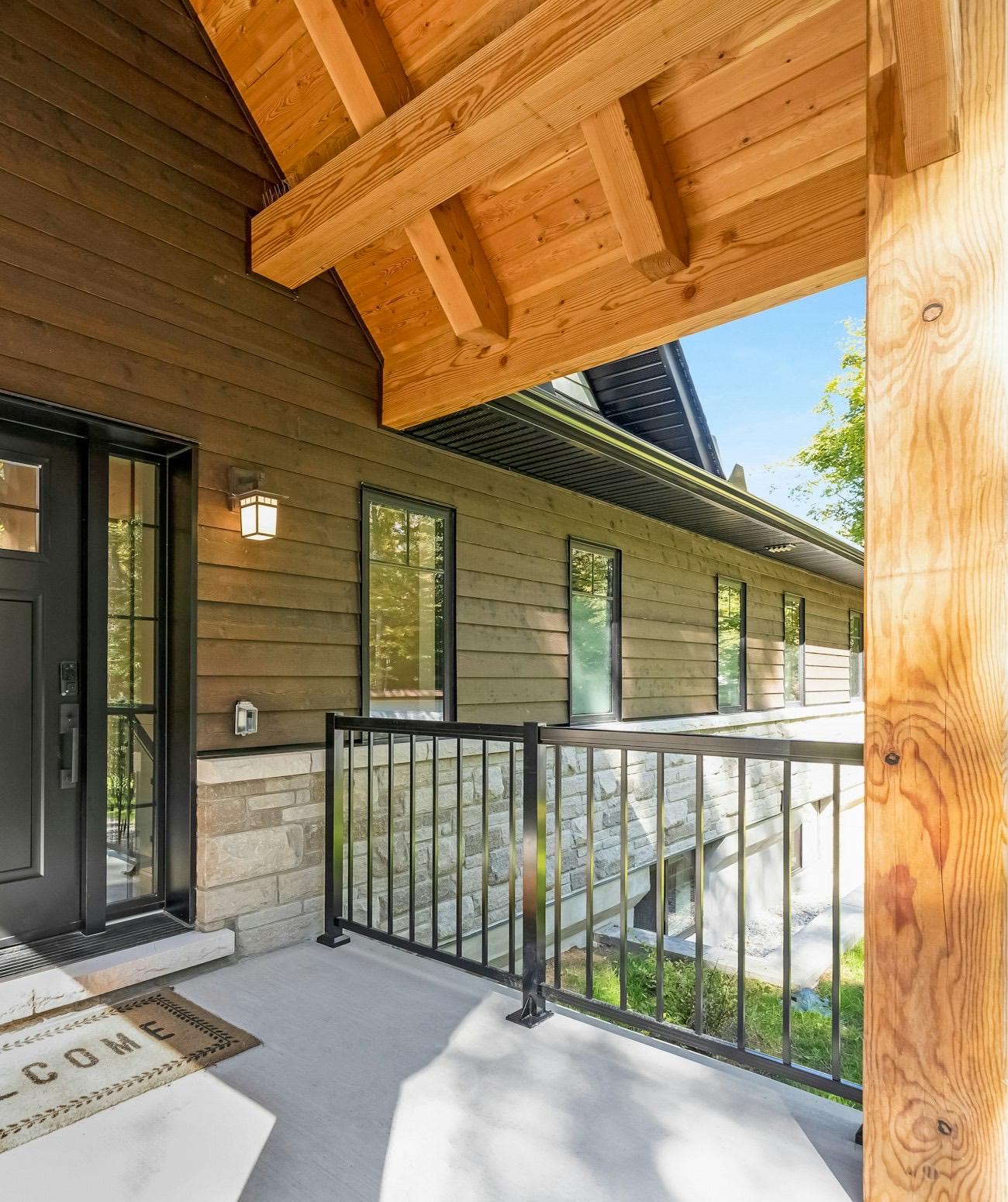A black front door with a welcome mat on a wooden porch